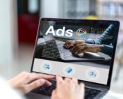 Computer screen with mockup of digital ads as person off screen types