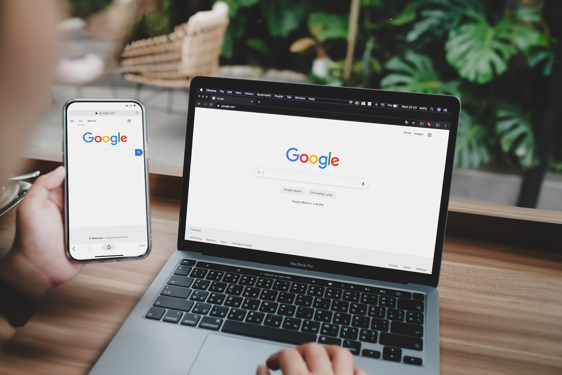 A man is typing on Google search engine from a laptop and phone.