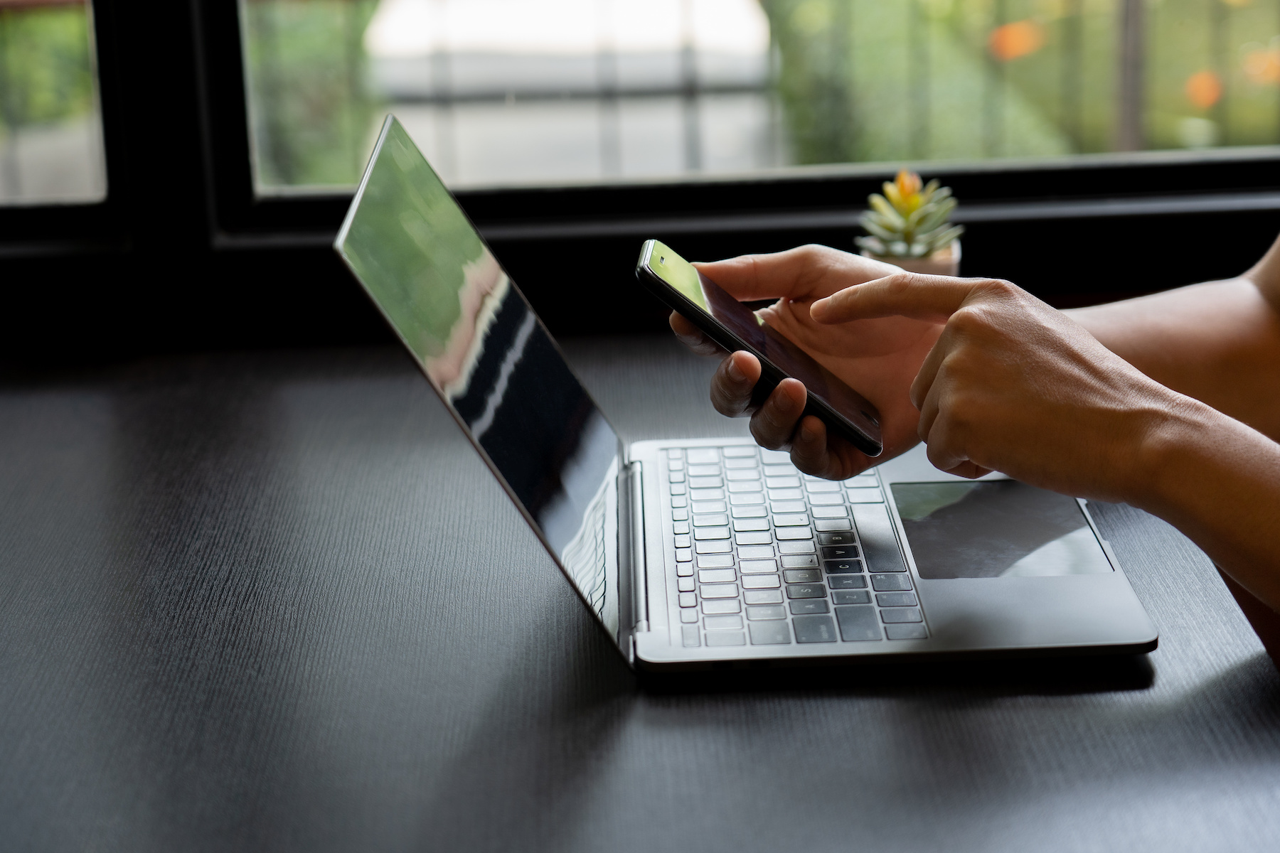 Person's hand deftly manipulated both mobile phone and notebook, engaged in the realm of online shopping.