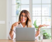 Woman sitting down is smiling at her laptop
