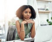 Portrait of woman with laptop at desk.