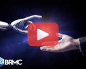 A robotic hand reaches out to meet a human hand in a symbolic gesture of connection, set against a futuristic, glowing background. A play button overlay is centered, and the BRMC logo appears in the lower-left corner.