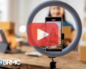 A young woman recording an online product presentation using a smartphone and a ring light, demonstrating the importance of video content for digital marketing.