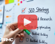 A hand writing an "SEO Strategy" checklist on a whiteboard, including keyword research, on-page optimization, and backlink building.