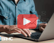 A person typing on a laptop with digital email icons and a large play button overlay, representing email marketing and communication.