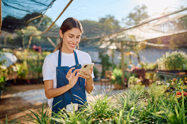 Woman working in plant nursery using her phone.